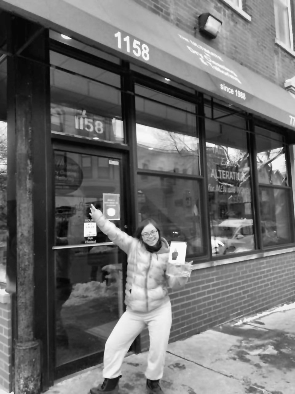 Black-and-white customer storefront image outside The Ultimate Dry Cleaning and Tailor Shop.
